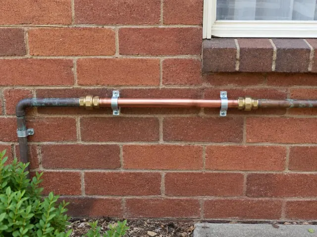 Repaired copper pipe section on a brick exterior wall beside a window in Maroubra
